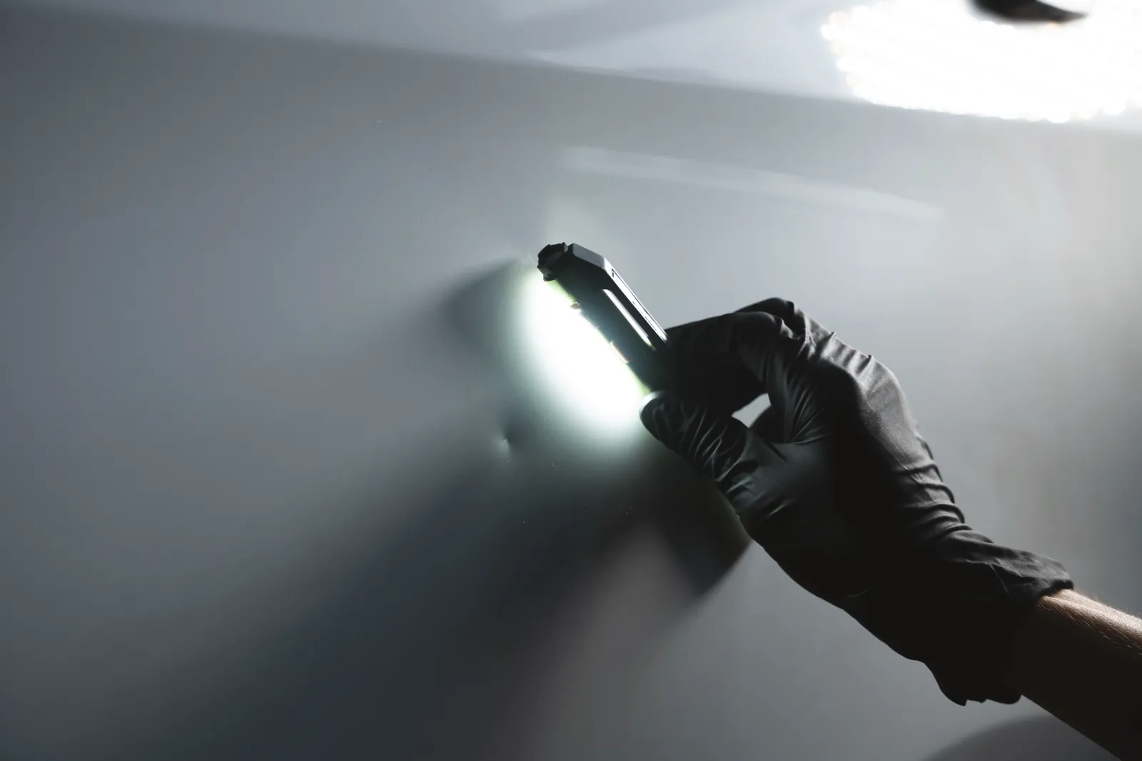 Dellenprüfung mit Handlampe am Karosserieblech bei FA-CARSERVICES