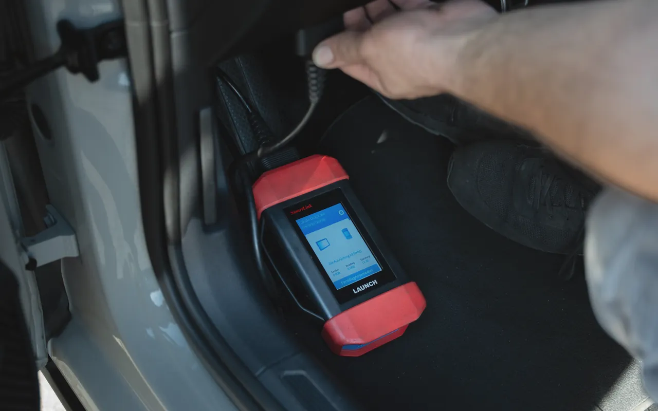 Diagnosegerät an der OBD-Schnittstelle im Fußraum bei FA-CARSERVICES