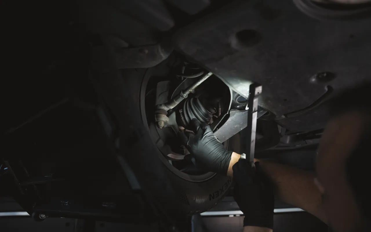 Unterbodenprüfung mit Handlampe an der Hinterachse bei FA-CARSERVICES