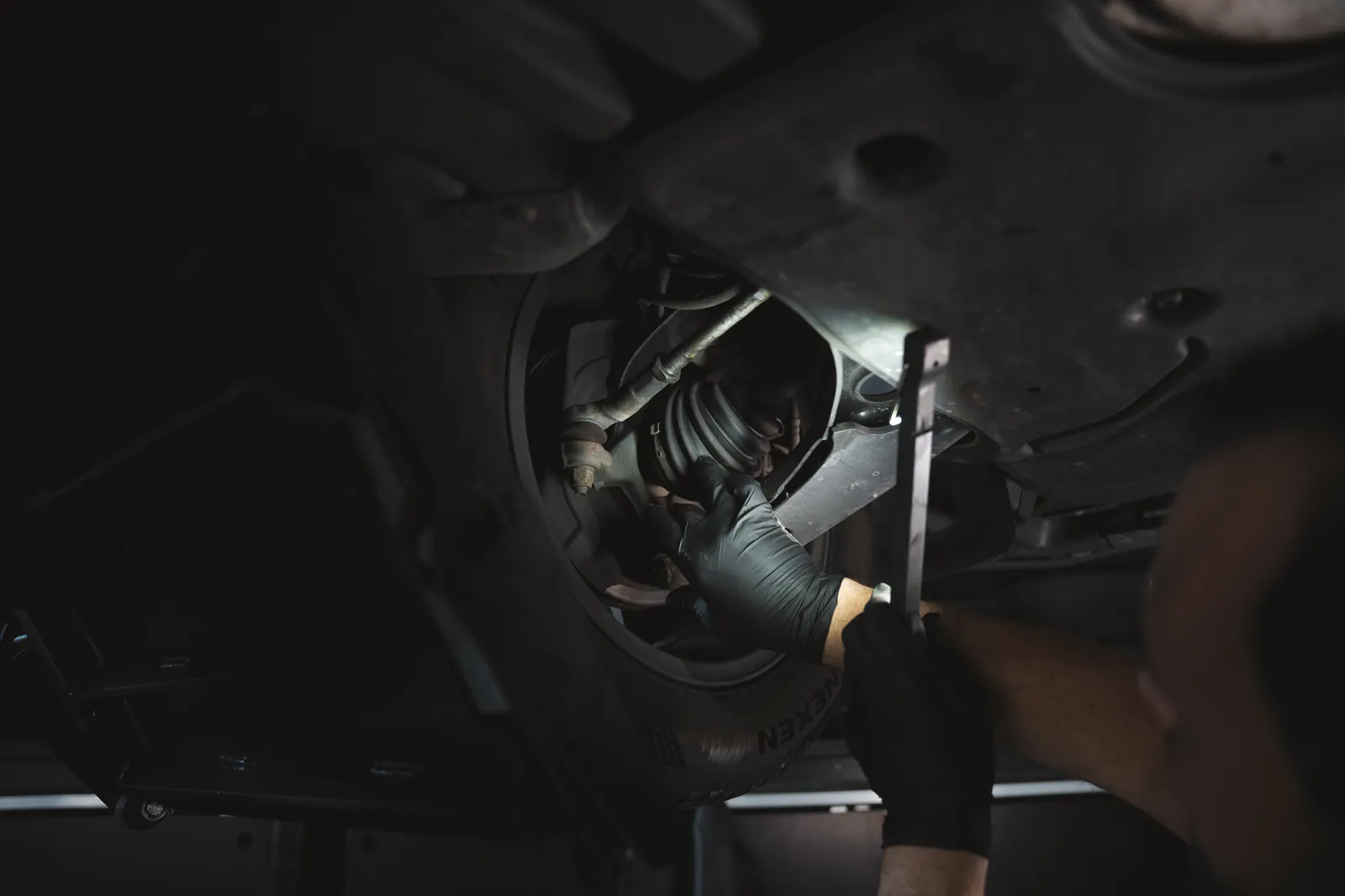 Unterbodenprüfung mit Handlampe an der Hinterachse bei FA-CARSERVICES